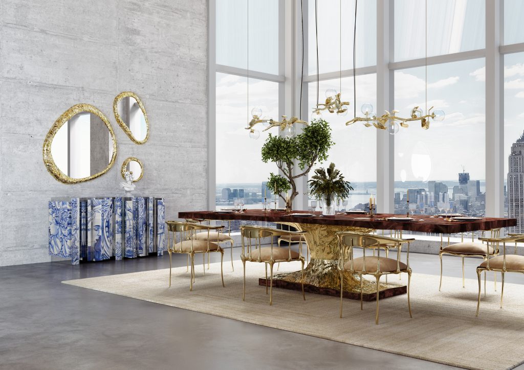 High-end dining room featuring a polished wood table with gold base, matching chairs, a blue-and-white tiled sideboard, and floor-to-ceiling windows.