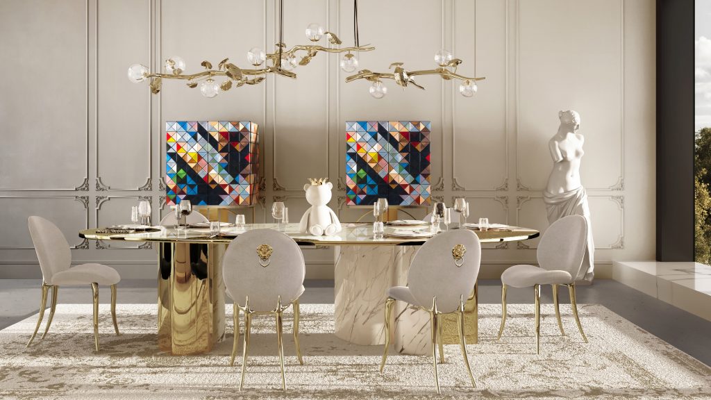 Modern dining area with a marble and gold table, plush chairs, colorful geometric cabinets, and an artistic leaf-inspired branch light fixture.
