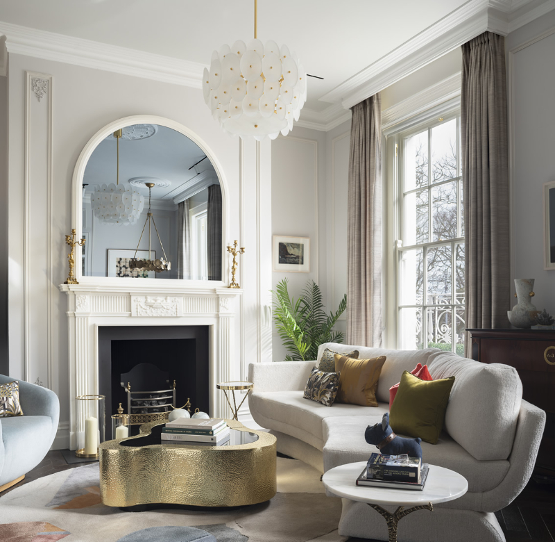 a classic living room with a white curved sofa ans a gold brass wave curved center table