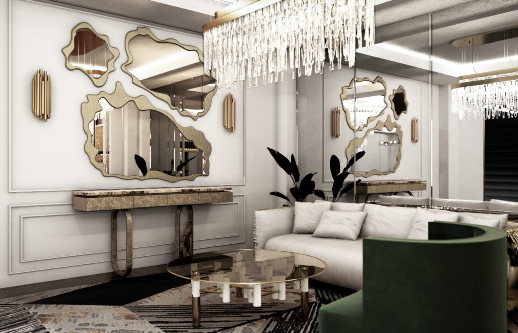 Cannes - living area with a chandelier, a grey sofa with golden details, a set of three mirrors, a green armchair and a round center table