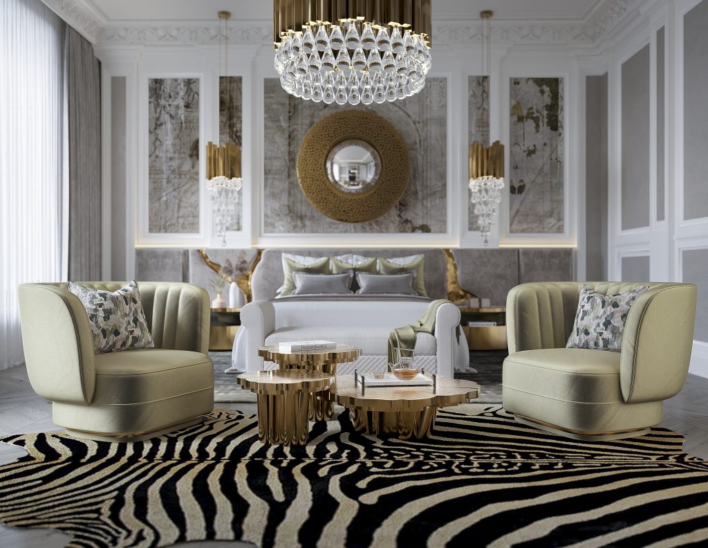 luxury houses - luxury master bedroom with a grey and golden headboard, two armchairs, a golden set of three center tables, two golden nightstands and a round mirror