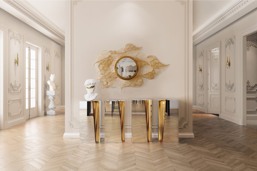 Modern Console Tables, A modern mirrored console table with golden folds, paired with a round mirror surrounded by a large, delicate gold filigree art piece on a neutral wall.