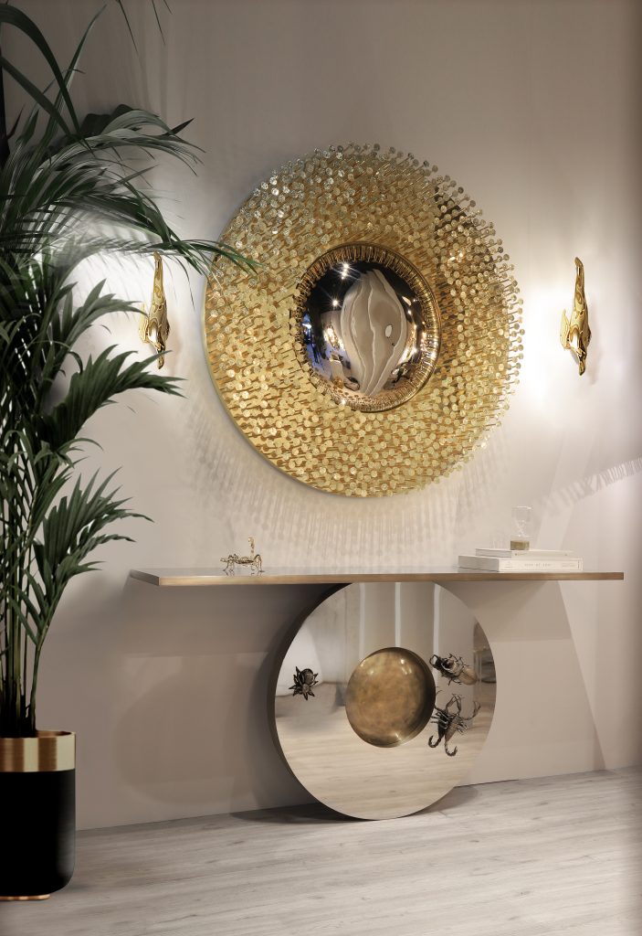 most-wanted- luxurious entrance, vase with plants, golden wall lamps, black sideboard with animals, books on top, round mirror with golden frame