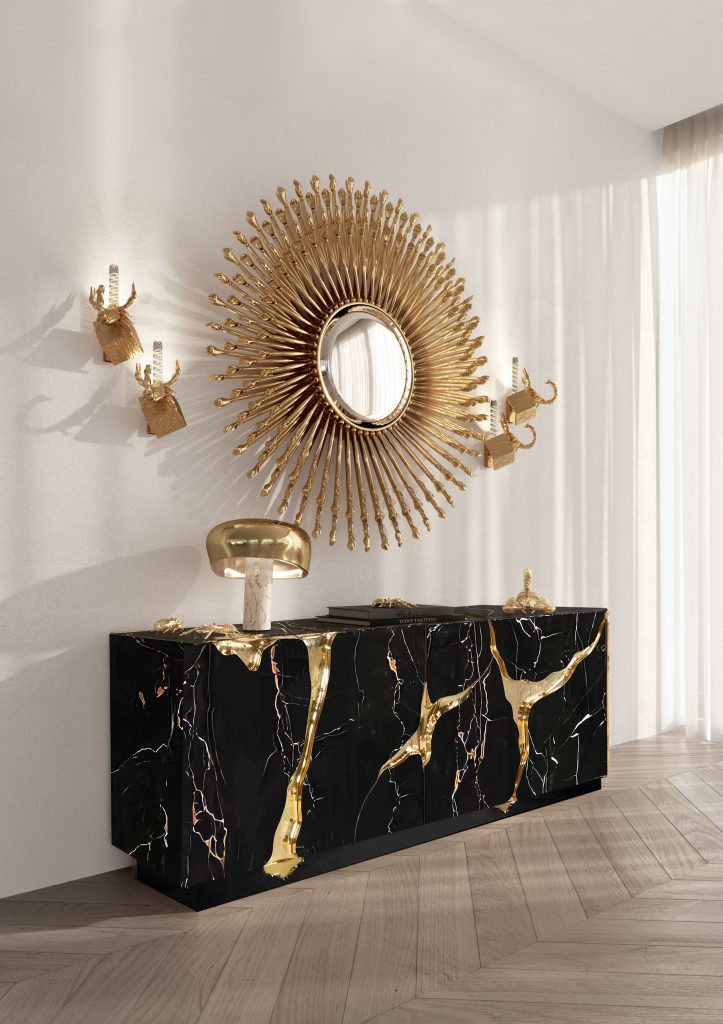 Gold and Black: Elegant Entryway with Black and Gold Decor: A luxurious entryway featuring a sleek black console table with gold accents, adorned with a stylish gold vase and black decorative items. Above the table, a large, gold-framed mirror reflects the light from an exquisite gold chandelier hanging from the ceiling. The walls are decorated with sophisticated black and gold patterned wallpaper, enhancing the overall elegance of the space. A plush black rug with gold detailing lies on the floor, welcoming guests into the opulent interior.