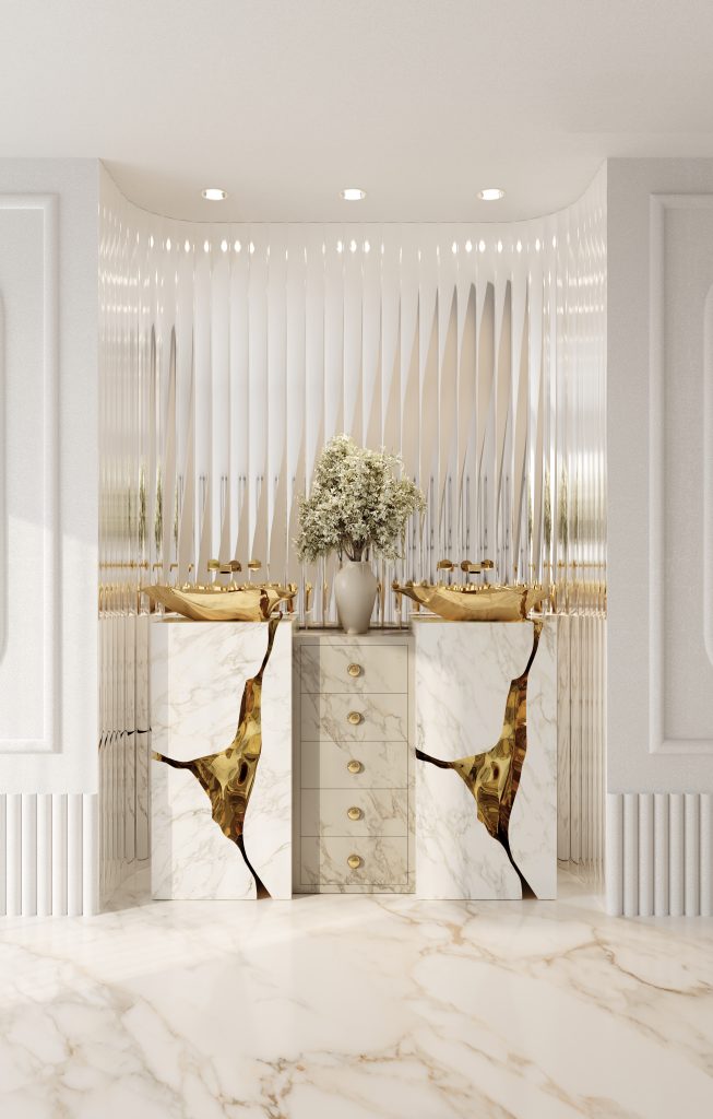 luxury bathroom - Bright and elegant bathroom vanity area with a modern, luxurious design. Two white marble pedestal sinks with bold gold accents flank a central marble cabinet with gold handles. Above the cabinet, a vase with white flowers adds a natural touch. The background features a textured, reflective white wall with a wavy pattern that enhances the clean and sophisticated atmosphere. The floor is also white marble with subtle veining, complementing the overall light and airy aesthetic.