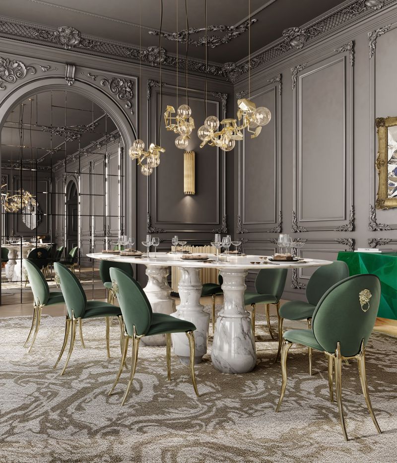 8 cadeiras verdes e douradas, mesa de jantar branca, 3 luminárias suspensas douradas, 1 espelho grande, 1 luminária de parede dourada, tapete branco e marrom, 1 aparador dourado e 1 aparador verde cadeiras de design