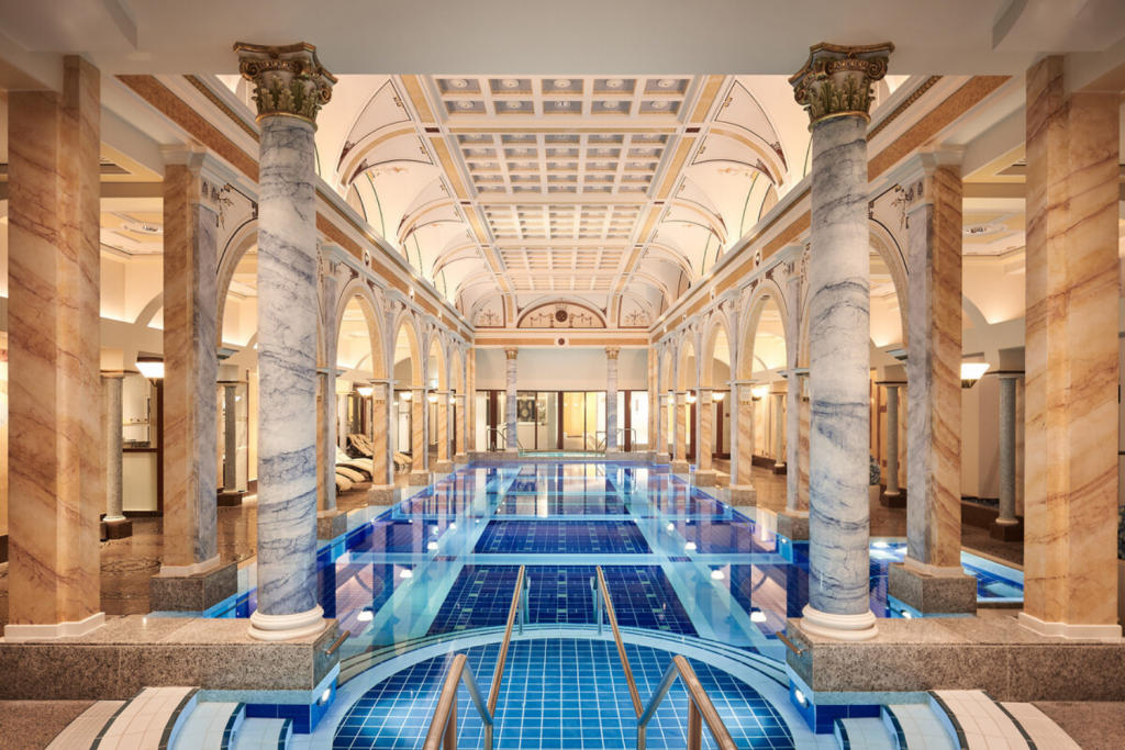 Luxury Thermal Baths in Europe, Luxury indoor thermal pool with marble Corinthian columns and ornate vaulted ceiling architecture.