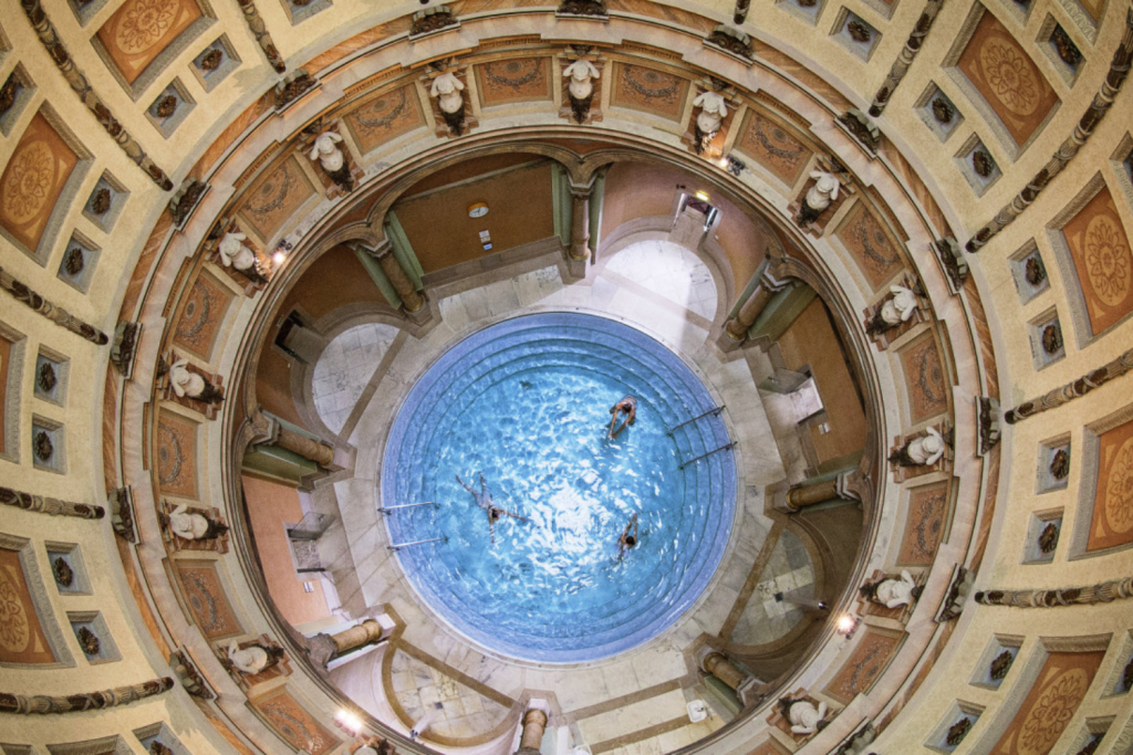 Luxury Thermal Baths in Europe, High-angle circular view of an ornate thermal bath with classical statues and domed ceiling.