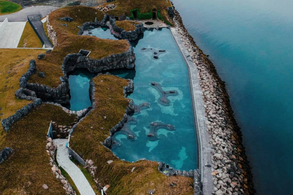 Luxury Thermal Baths in Europe, Aerial view of an organic-shaped thermal pool built into rocky terrain next to the ocean.