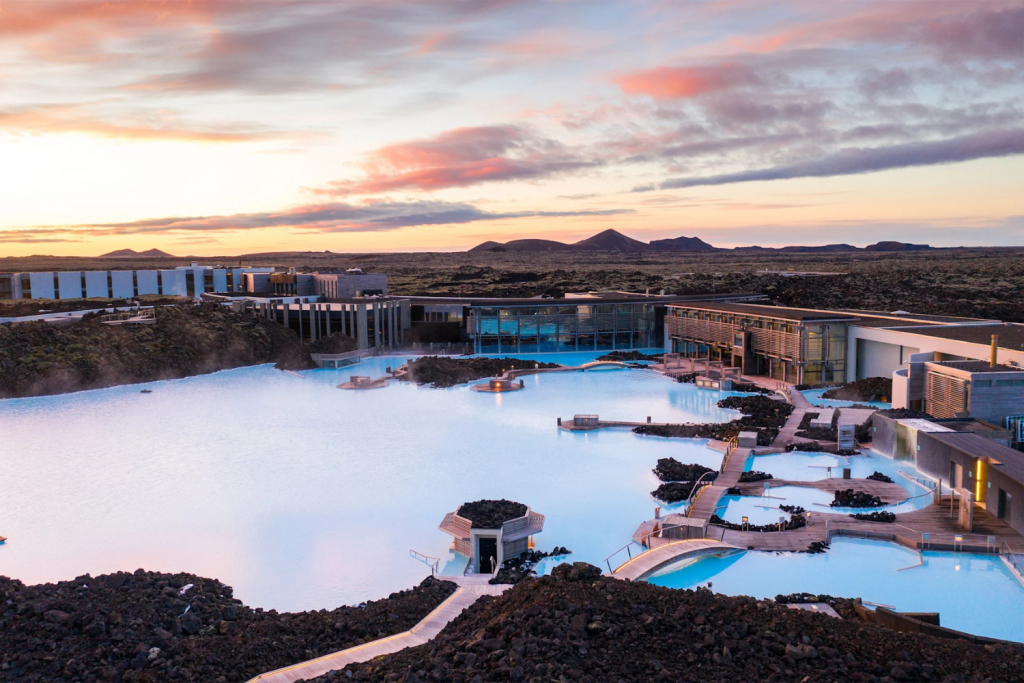 Luxury Thermal Baths in Europe, Milky blue geothermal waters of the Blue Lagoon Iceland with black lava rocks at sunset.