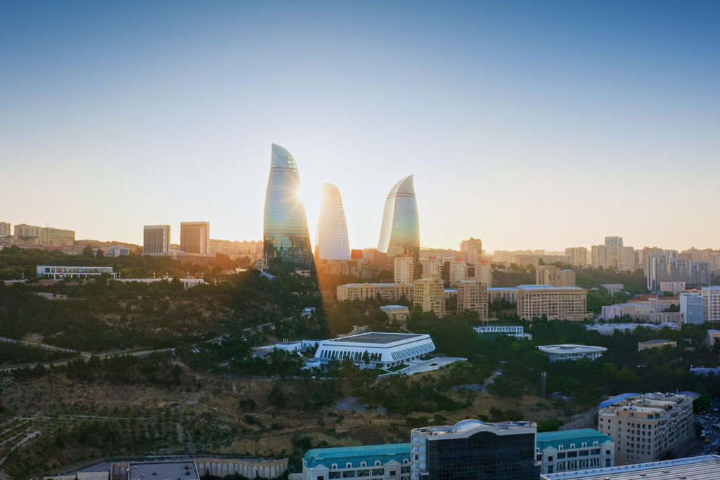 architecture events 2026, Panoramic view of the Flame Towers skyscrapers in Baku, Azerbaijan, during sunrise, overlooking the city skyline and Caspian Sea coast.