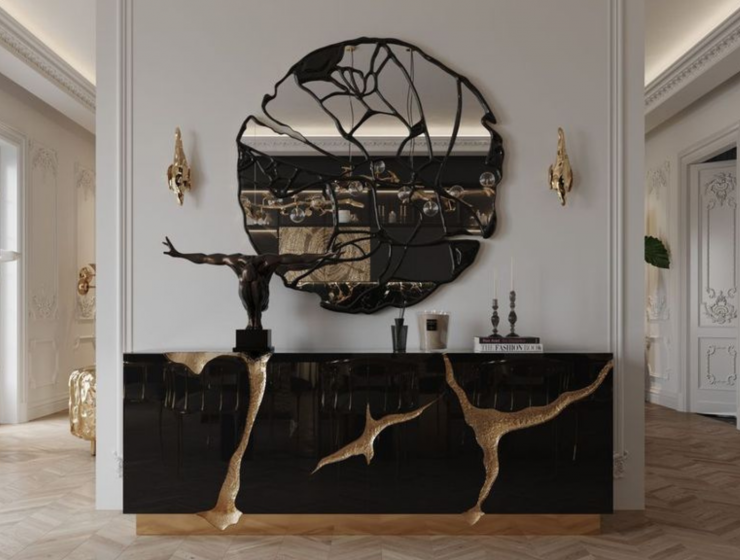 Luxury modern classic entryway featuring Boca do Lobo's iconic black and gold Lapiaz Sideboard paired with a striking organic black mirror and classic sculptures.