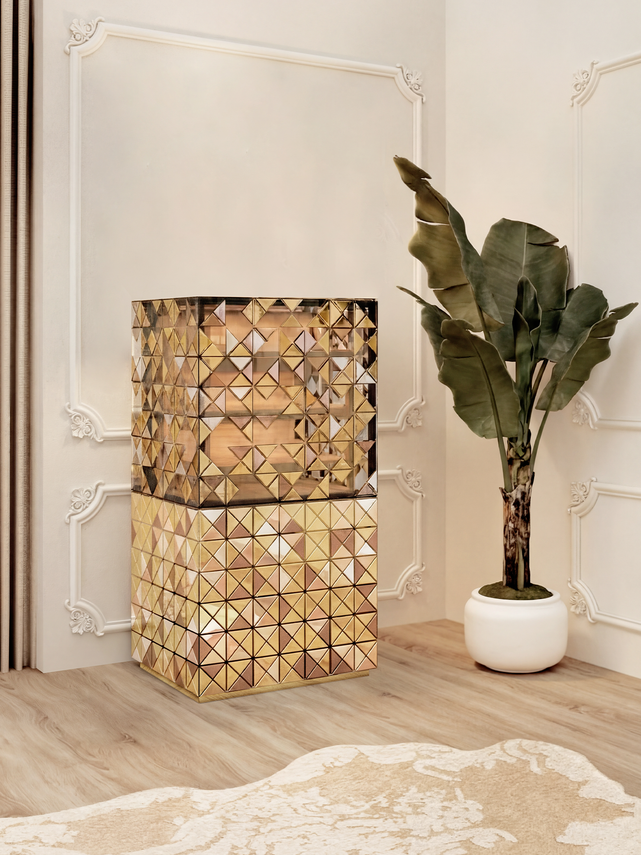 Habano Cabinet, A luxurious, tall rectangular cabinet featuring a "pixelated" surface made of hundreds of small gold and bronze triangular mirrors. It is positioned in a neo-classical room with white wall moldings, a large leafy potted plant, and a light wood floor with a textured cream rug.