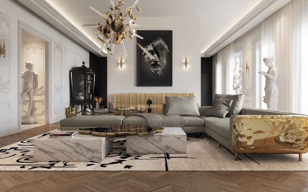 A luxurious living room featuring a gray sectional sofa with a polished gold side panel, a white marble coffee table, classic wall moldings, classical statues, and an abstract gold chandelier., stone coffee tables