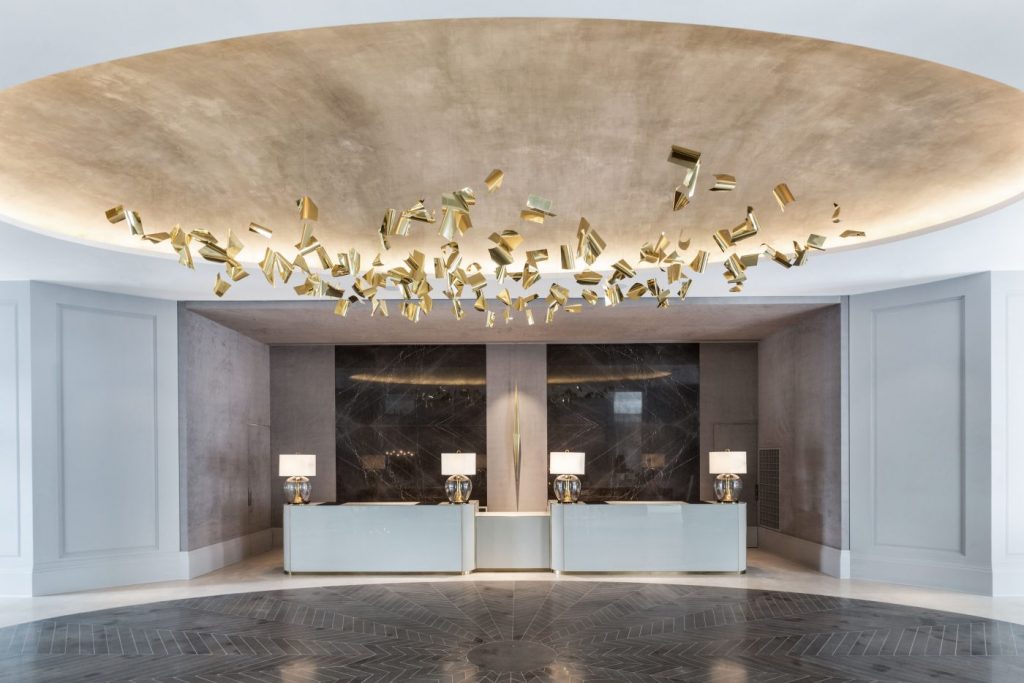 Hotel reception lobby with gold suspended sculpture and marble front desk – melhores hoteis em sao paulo