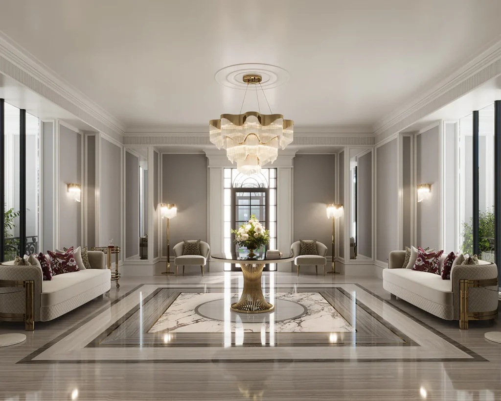 Grand formal hallway with symmetrical cream sofas and armchairs, a gold pedestal round table with floral centerpiece, marble inlay flooring, and a tiered gold and glass scalloped chandelier. kunal trehan