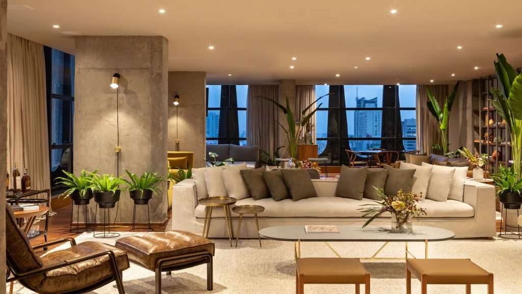 Modern hotel lounge with concrete pillars, plush sofas and night city view – melhores hoteis em sao paulo