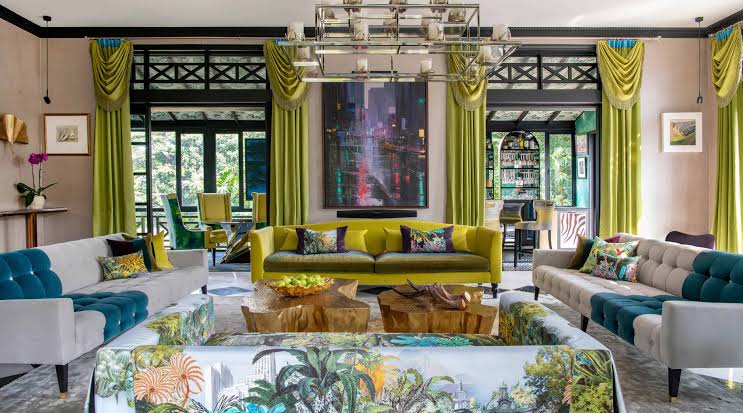 Opulent living room interior featuring plush sofas, large windows with green curtains, and artistic coffee tables, luxury brand