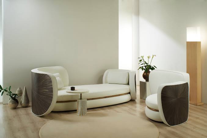 Modern white daybed and armchair with dark wood rounded panels in a minimalist interior, luxury brand