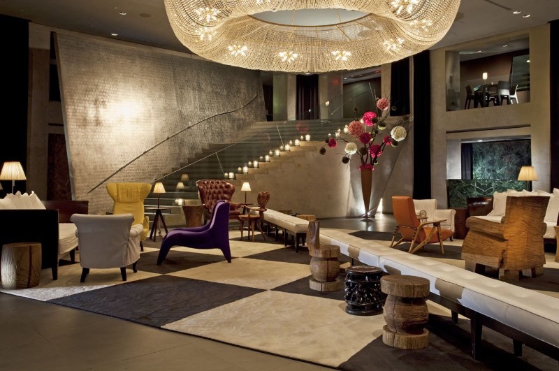 hotel paramount New York – Expansive and eclectic lounge area with designer furniture, geometric rugs, and a colossal cascading chandelier.