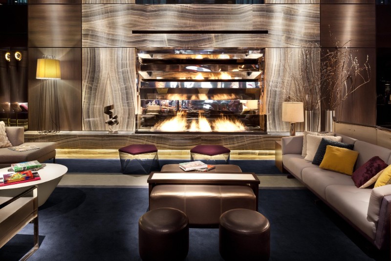 hotel paramount New York – Modern fireplace set into a striking veined marble wall, complemented by cozy sofas and warm gold accents.