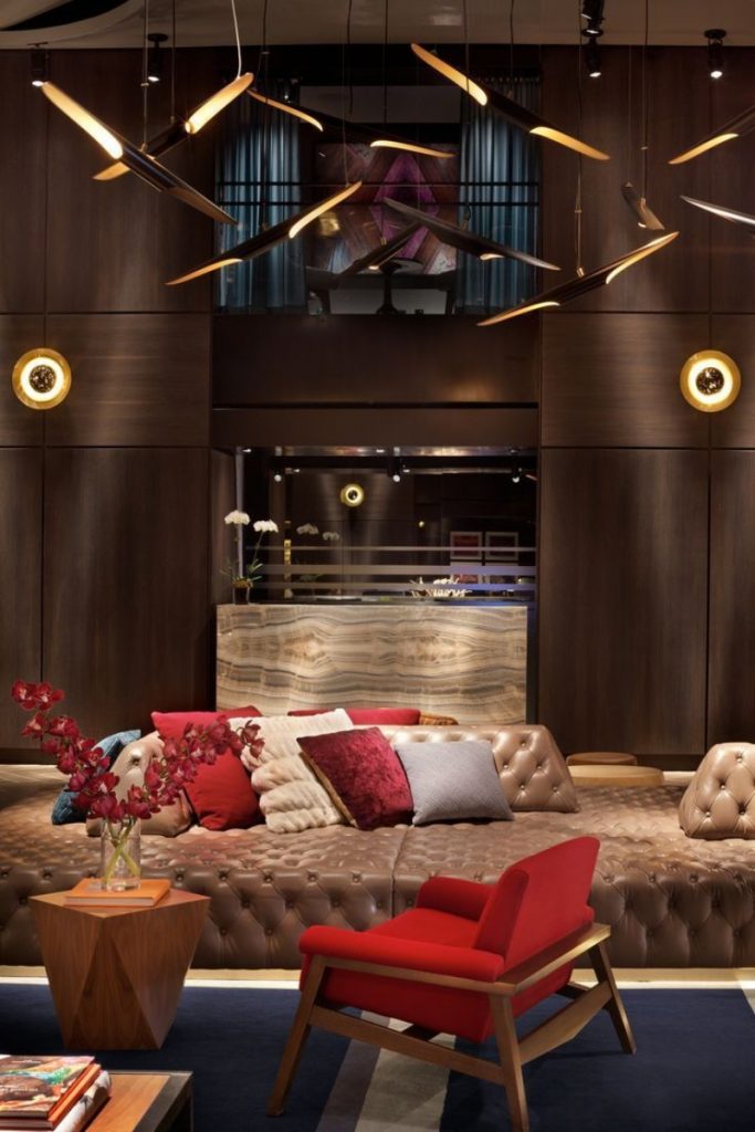 hotel paramount New York – Close-up of the lobby with a tufted leather sofa, a striking red armchair, and avant-garde sculptural ceiling pendant lights.
