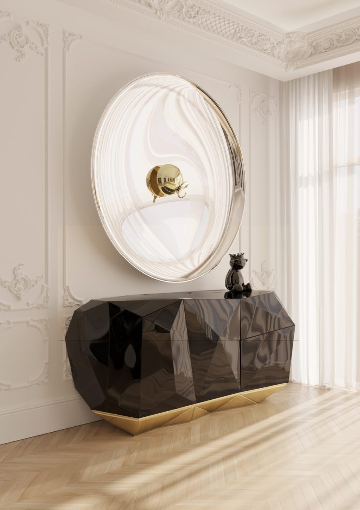 Modern black diamond sideboard with gold accents under a large round mirror in a classic room.