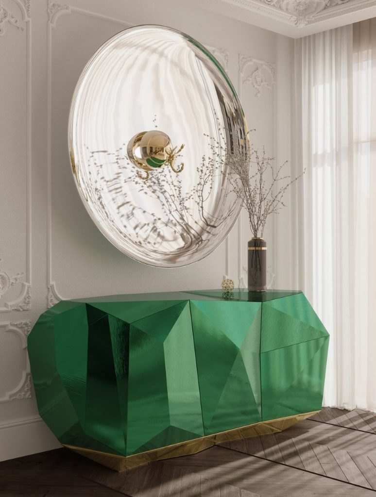 Elegant luxury entryway featuring Boca do Lobo’s emerald-green Diamond Sideboard, paired with a large round statement mirror and classical wall details.