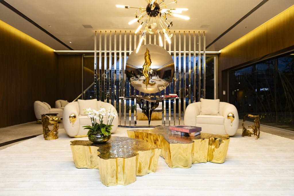 Contemporary luxury living room featuring Boca do Lobo gold furniture, sculptural coffee tables, white sofas and statement lighting.
