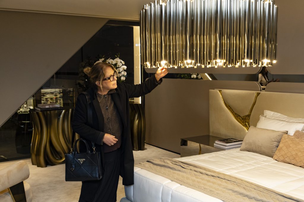 Boca do Lobo bedroom showroom in Brazil featuring luxury furniture and statement pieces, with a man admiring a distinctive designer lamp in an elegant interior.