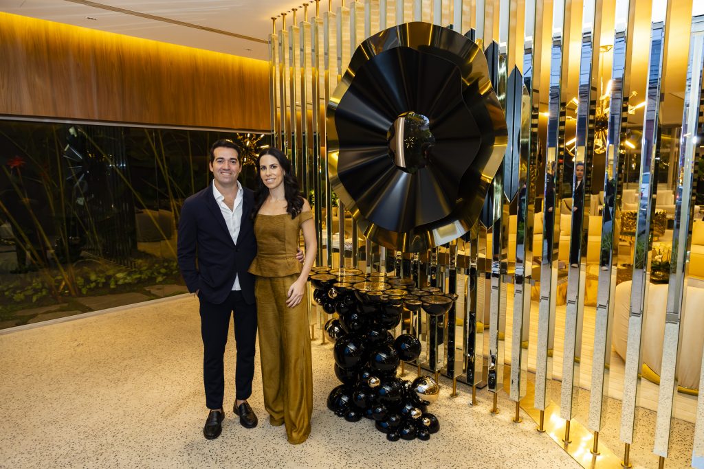 Couple standing at the entrance of the Boca do Lobo showroom in Brazil, with a black and gold console table and matching black and gold mirror creating an elegant and luxurious interior.