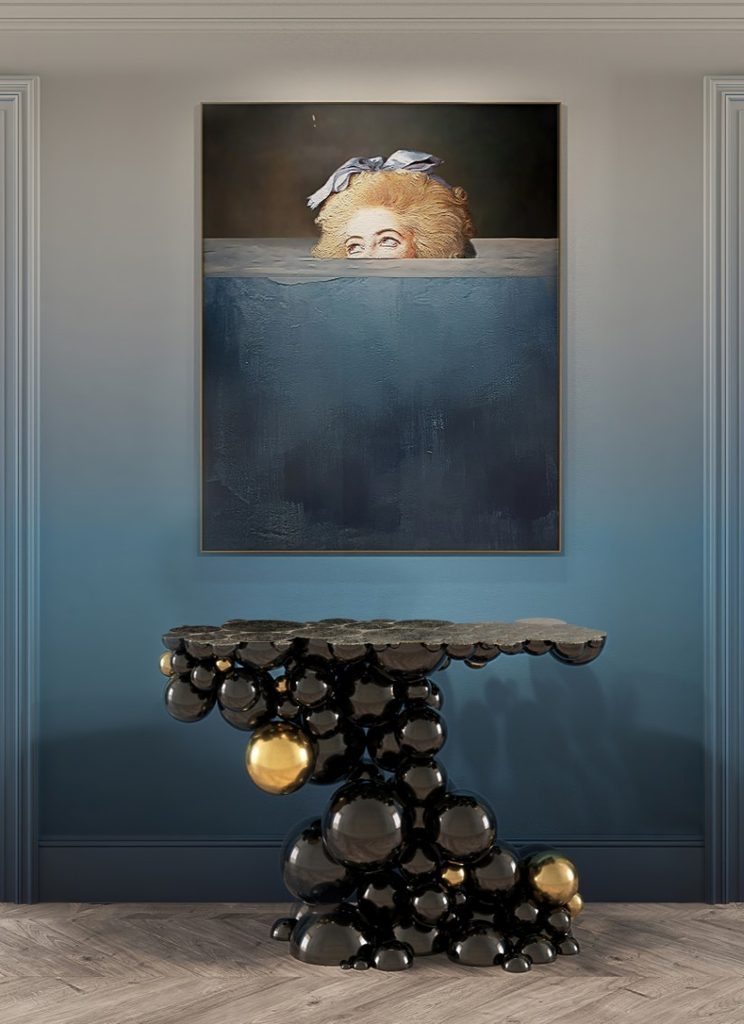 Luxurious blue entryway featuring Boca do Lobo’s Newton Console, with its sculptural black and gold sphere design, beneath a statement artwork.