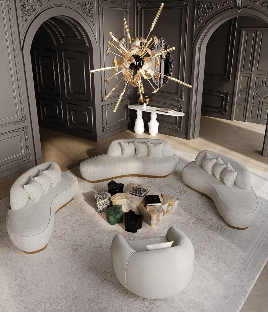 Luxury living room with curved beige sofas, sculpted coffee tables, and a dramatic gold starburst chandelier.