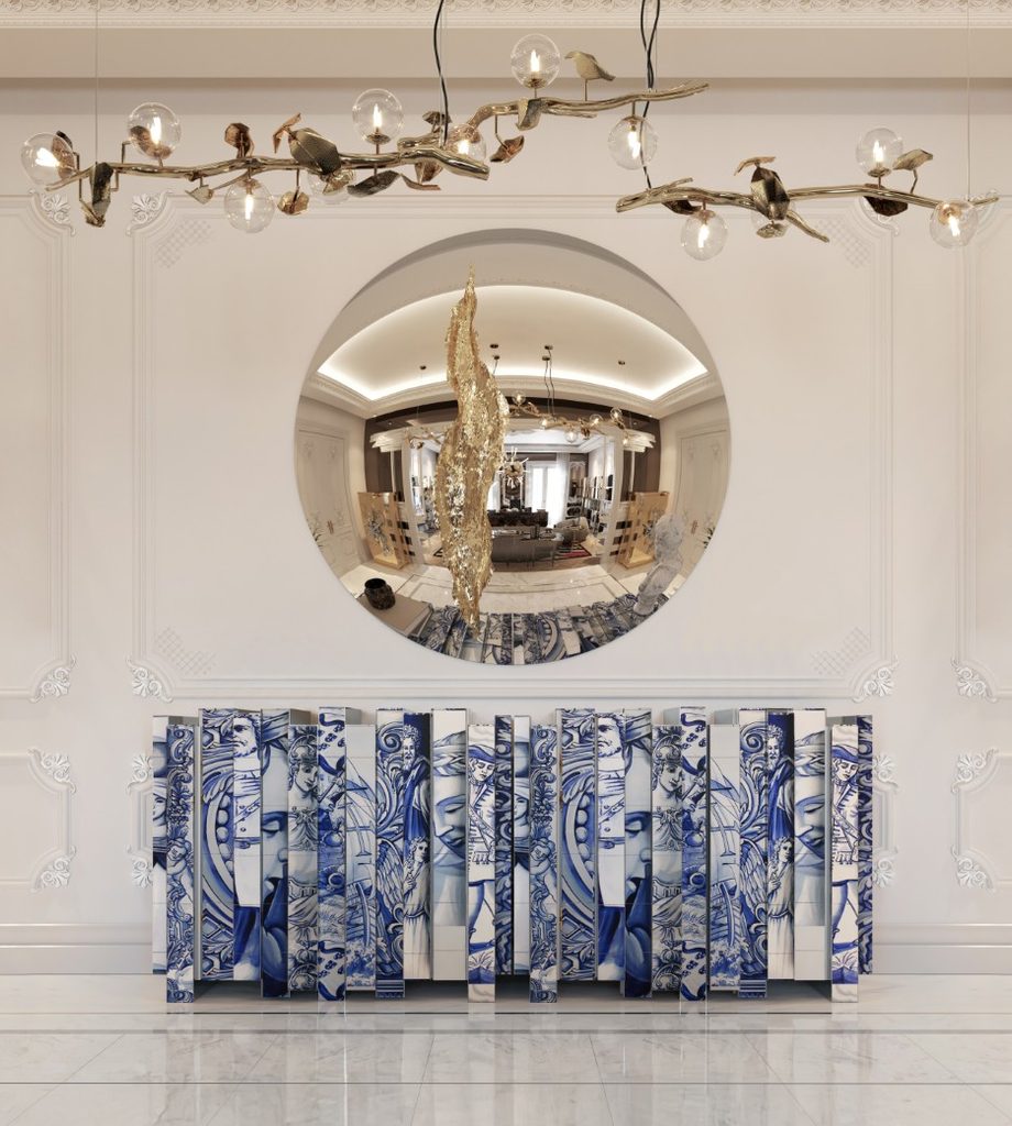 Luxury entrance foyer featuring the blue and white Heritage Sideboard, golden Lapiaz Mirror, and botanical Hera Suspension Lamp against ornate white walls.