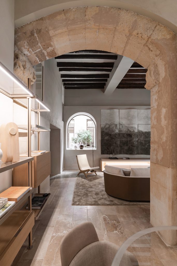 Earthy neutral living lounge framed by historic stone arch, luxury showrooms in Palma de Mallorca