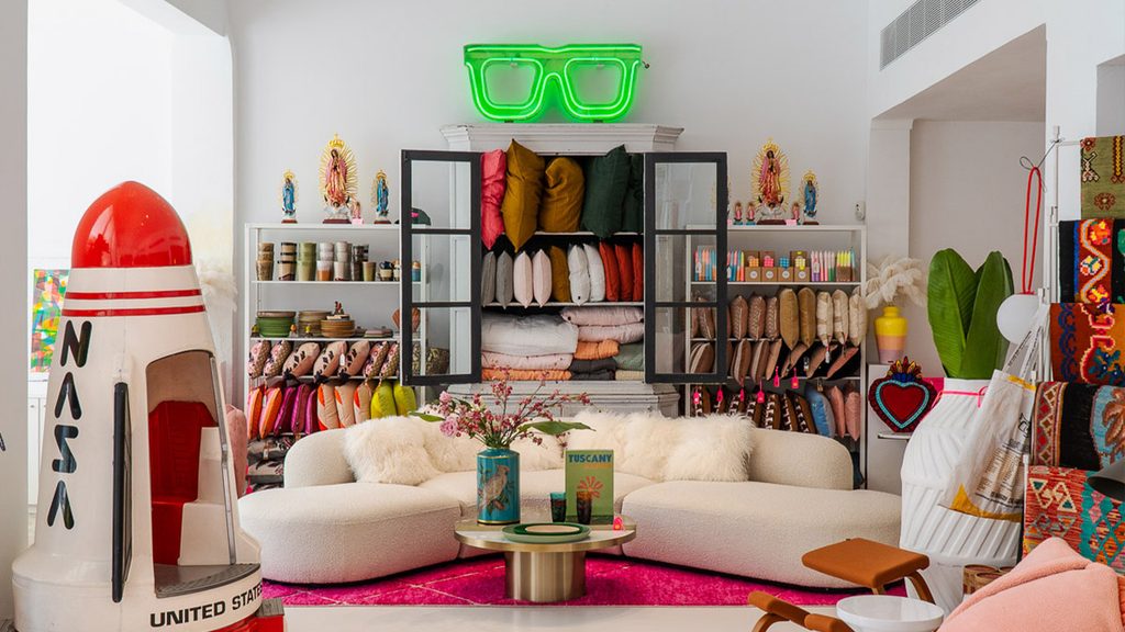 Eclectic showroom with white curved sofa, neon sign, and decor items, luxury showrooms in Palma de Mallorca