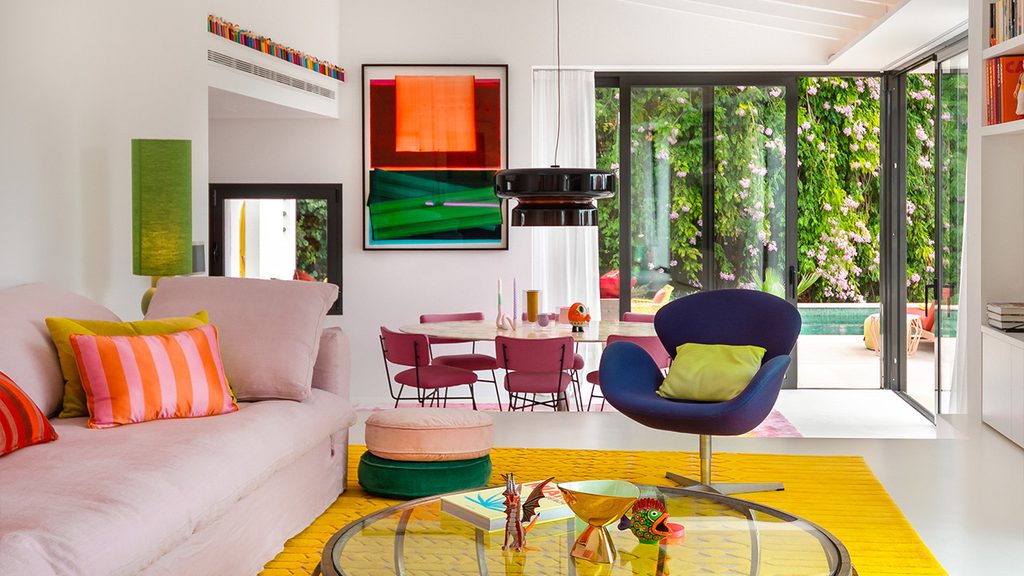 Vibrant living space with pink sofa, yellow rug, and colorful art, luxury showrooms in Palma de Mallorca
