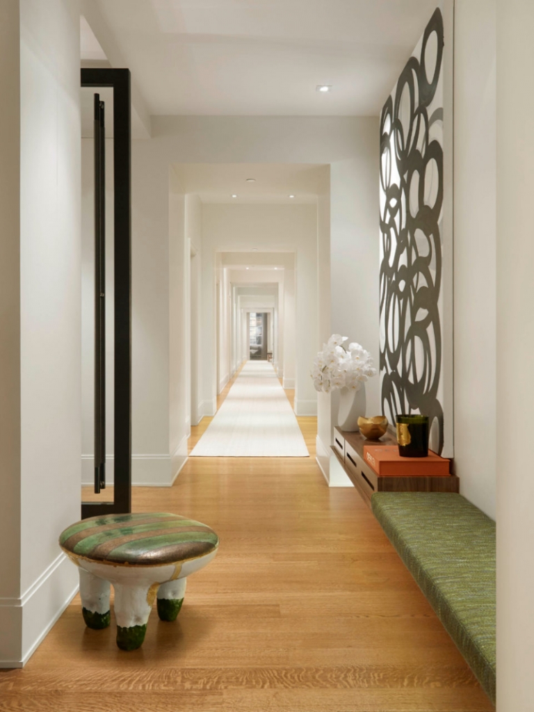 Pembrooke & Ives - A large corridor ini straight line, a green texture bench in the hallway and a big painting on the wall