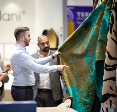 INDEX Dubai 2024- There are 2 men evaluating a piece of fabric. They are inside a warehouse.