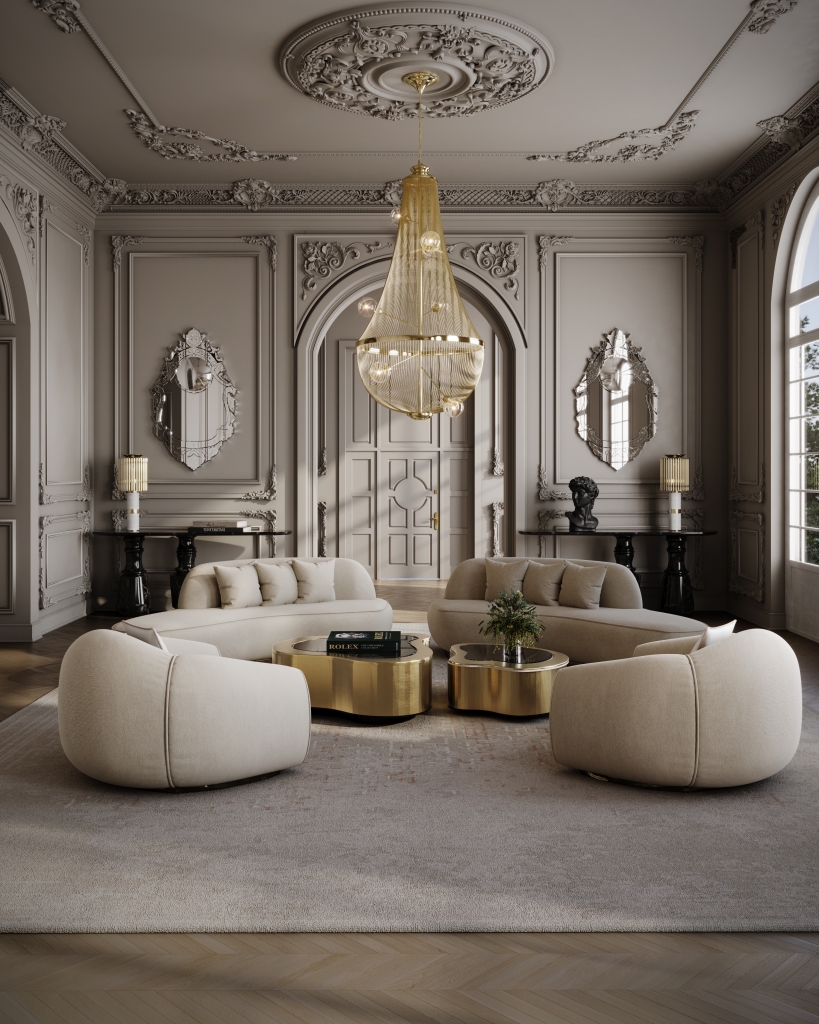 modern interior design - Luxurious classic living room with ornate ceiling and wall moldings, featuring a large gold pendant chandelier as the centerpiece. The space includes four beige curved sofas arranged around two shiny gold coffee tables on a light grey rug. The room has tall arched windows on the right and decorative mirrors and lamps on black console tables against the walls.
