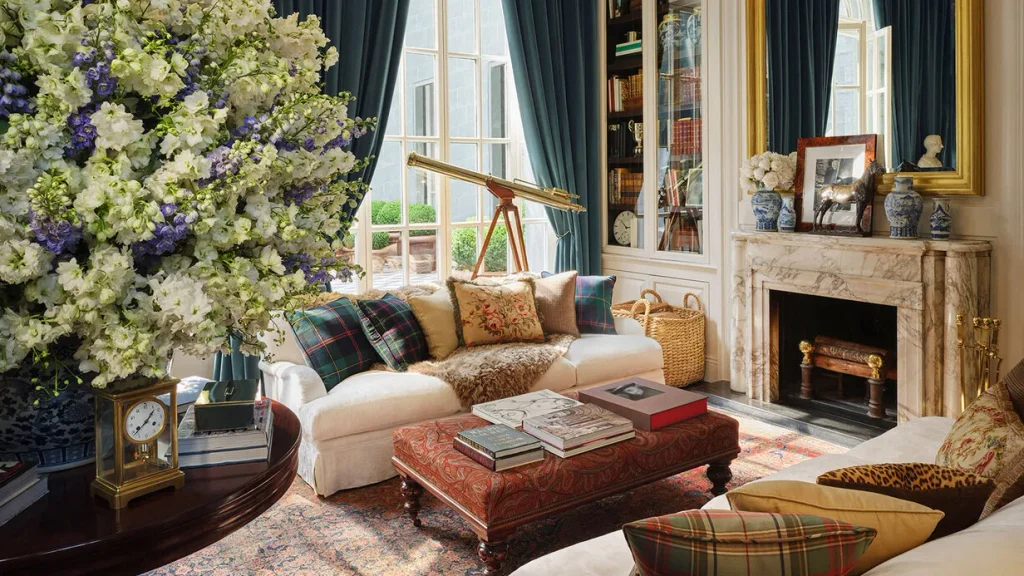 Elegant living room with a white sofa, marble fireplace, blue curtains, and a large floral arrangement
