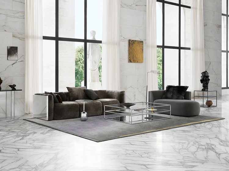 Contemporary living room with marble walls, brown sofa, grey chaise lounge, and a glass coffee table.