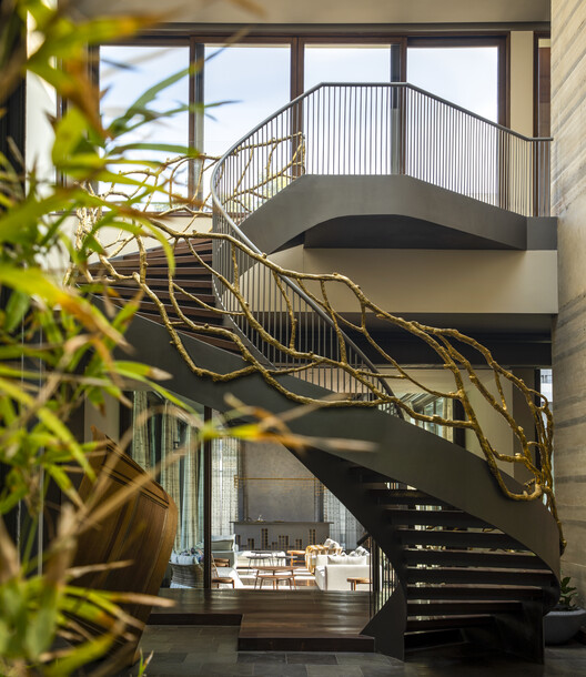 Spiral staircase with golden branch railing, luxury interior designers in India
