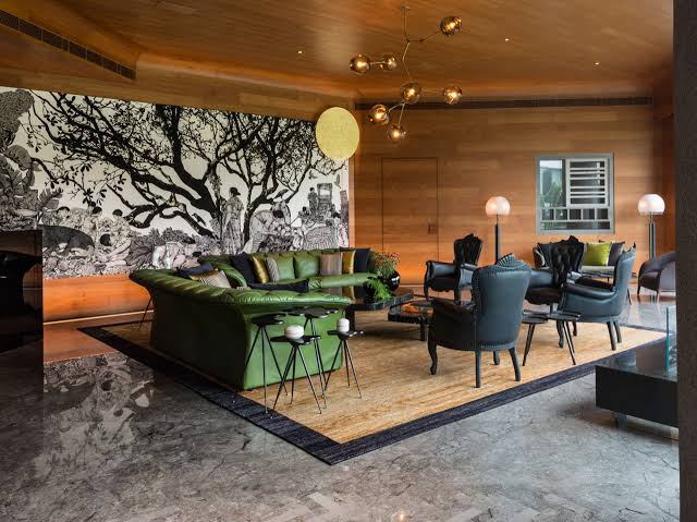 Spacious lounge with green sofa and art wall, luxury interior designers in India