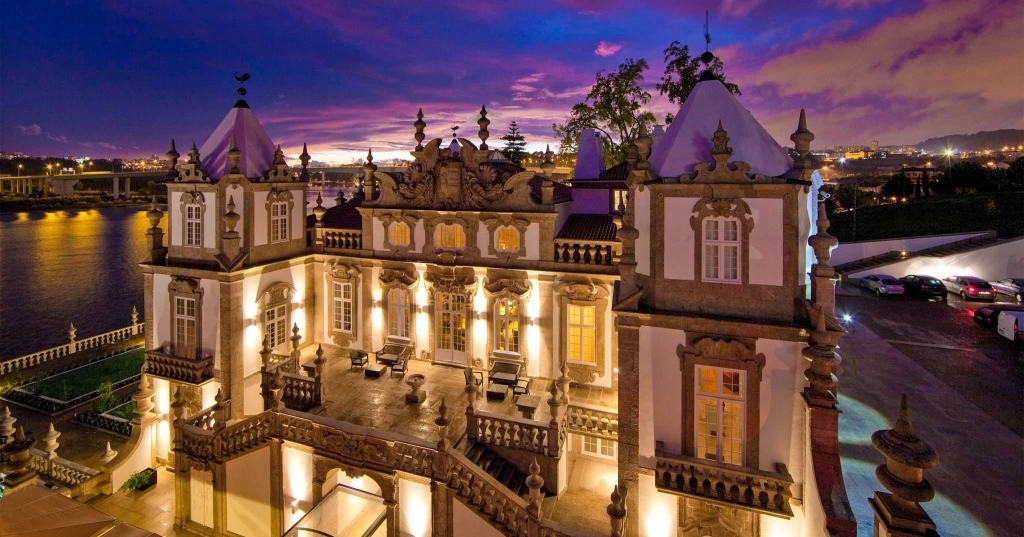Historic Portuguese palace facade illuminated at dusk by the river -pestana