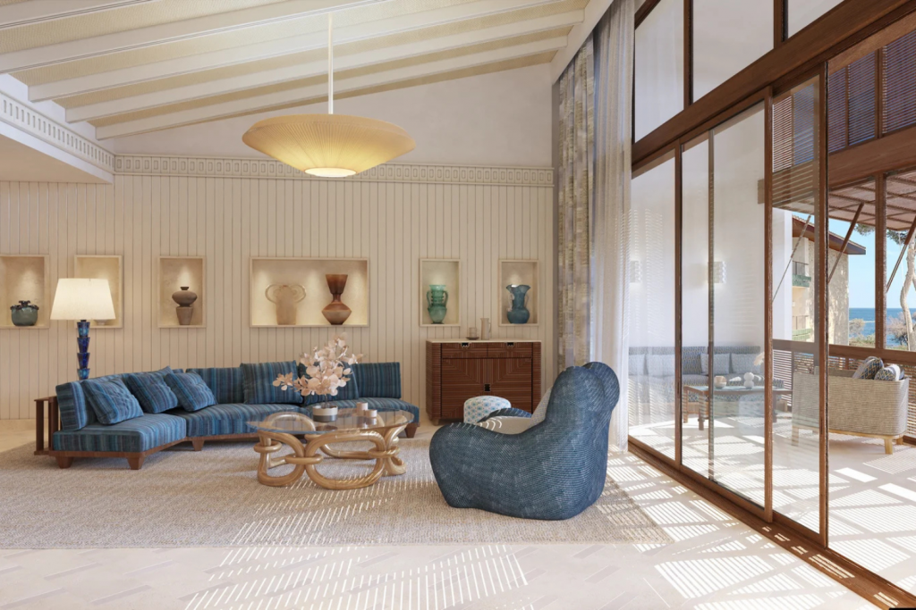 Luxury Hotels Opening in 2026, Modern coastal living room with a blue striped sectional sofa, woven armchair, and floor-to-ceiling glass doors.