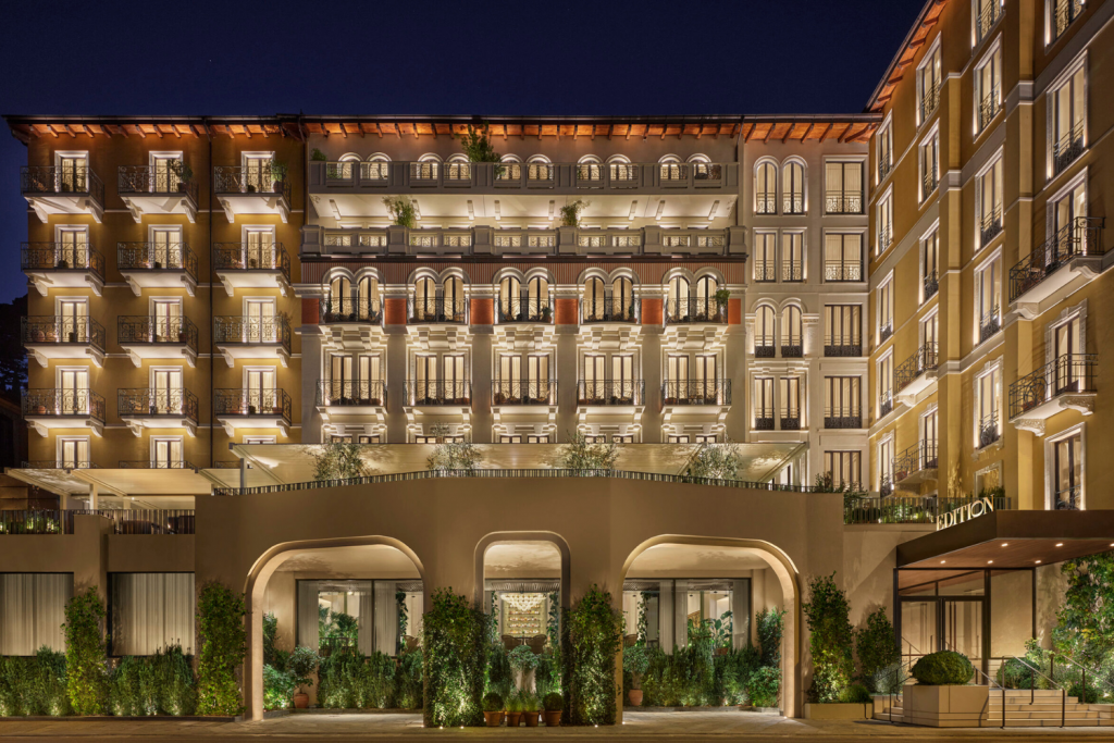 Luxury Hotels Opening in 2026, Night view of The Edition Hotel facade featuring illuminated balconies and a grand arched entrance with greenery.