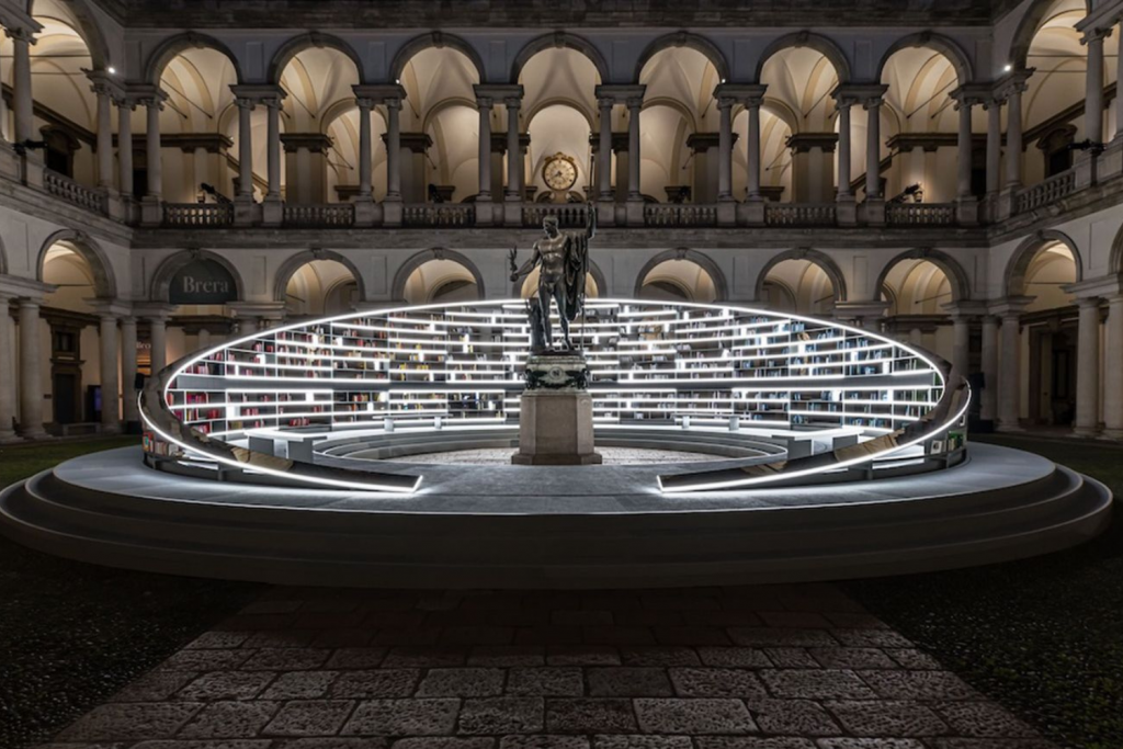 Immersive installation at Milan Design Week featuring a circular illuminated structure surrounding a classical sculpture in a historic architectural courtyard. Milan Design Week 2026