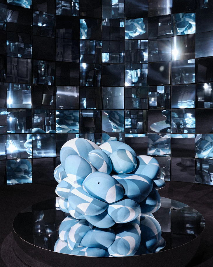 Sculptural chair made of blue and white patterned pillows in a room with mirrored walls. Objets Nomades