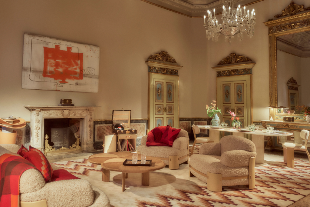 A lavishly decorated living room featuring plush armchairs, a marble fireplace, an ornate chandelier, and classical gold-trimmed doorways, Objets Nomades
